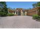 Inviting home featuring a brick driveway, two-car garage, lush landscaping, and an arched entryway at 140 Seville Chase Dr, Winter Springs, FL 32708