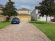 Paver driveway leading to a yellow two-car garage at 15208 Avenue Of The Arbors, Winter Garden, FL 34787