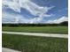 Expansive green field under a bright blue sky filled with fluffy clouds at 15208 Avenue Of The Arbors, Winter Garden, FL 34787