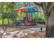 Community playground surrounded by mature trees, featuring colorful play equipment and mulch ground cover at 15208 Avenue Of The Arbors, Winter Garden, FL 34787