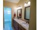 Bathroom featuring dual sinks, granite countertops, decorative mirrors, and vanity cabinets at 1550 Kevin Ln, Deland, FL 32724