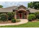 Close-up of the brick-arched front entrance with a red door and landscaped surroundings at 1550 Kevin Ln, Deland, FL 32724