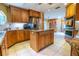 A spacious kitchen with stainless steel refrigerator, center island, wood cabinetry and tiled floor at 1550 Kevin Ln, Deland, FL 32724