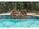Close-up of waterfall feature in screened-in pool with blue tile trim at 1550 Kevin Ln, Deland, FL 32724