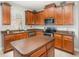 Well-lit kitchen featuring wood cabinets, stainless steel appliances, and center island with brown countertop at 15606 Montesino Dr, Orlando, FL 32828