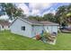 Charming light blue home, showing a well-maintained backyard with green grass and mature trees at 2597 Cr 426F, Lake Panasoffkee, FL 33538