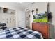 Comfortable bedroom with a checkered bedspread, dark wood dresser and a guitar on the wall at 2597 Cr 426F, Lake Panasoffkee, FL 33538