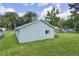 Home's light blue exterior and large backyard featuring lush green grass and privacy fencing at 2597 Cr 426F, Lake Panasoffkee, FL 33538