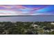 Scenic aerial view of a residential area with lush greenery and a large body of water in the distance at sunset at 328 E Minnehaha Ave, Clermont, FL 34711
