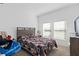 Cozy bedroom with carpet floors, a queen-sized bed with patterned bedding and plenty of natural light at 4223 Little Owl Ln, Kissimmee, FL 34746
