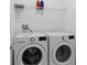 Well-lit laundry room with modern washer and dryer and overhead shelf at 4223 Little Owl Ln, Kissimmee, FL 34746