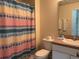 Bathroom features a colorful shower curtain, a toilet, and a vanity with sink and a mirror, well maintained at 4778 Vero Beach Pl, Kissimmee, FL 34746
