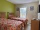 Comfortable bedroom showcasing twin beds with colorful bedding and a bright window offering scenic views at 4778 Vero Beach Pl, Kissimmee, FL 34746