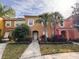 Charming two-story townhome with colorful facade, lush landscaping, and tropical palm trees, offering inviting curb appeal at 4778 Vero Beach Pl, Kissimmee, FL 34746
