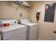 Functional laundry room featuring a washer, dryer, storage shelf, and a fire extinguisher for added safety at 4778 Vero Beach Pl, Kissimmee, FL 34746