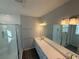 Well-lit bathroom with double sinks, a long vanity, a glass-enclosed shower, and modern fixtures at 551 Pothos St, Apopka, FL 32703