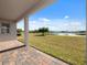 A covered back porch with brick pavers with a pond and grassy area view at 5550 Sabal Dr, St Cloud, FL 34771
