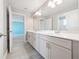 Bathroom with double sinks, white cabinetry, chrome fixtures, and gray tile flooring at 5550 Sabal Dr, St Cloud, FL 34771