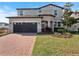 Charming two-story home featuring a stone entryway, brick driveway, well-kept lawn, and attached two-car garage at 5550 Sabal Dr, St Cloud, FL 34771