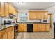 Bright kitchen featuring wooden cabinets, black appliances and neutral tile flooring at 618 Acapulca Way, Altamonte Springs, FL 32714