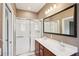 Bathroom featuring double sinks, a shower with sliding glass doors, and decorative brown wallpaper at 8430 Leatherleaf Ln, Orlando, FL 32827