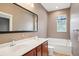 Bathroom featuring double sinks, a soaking tub, brown wallpaper, and a large mirror at 8430 Leatherleaf Ln, Orlando, FL 32827