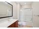 Bathroom featuring a tub with glass doors, vanity, and dark framed mirror at 8430 Leatherleaf Ln, Orlando, FL 32827