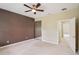 Well lit bedroom featuring tan carpet, dark wallpaper, a mirrored closet, and access to another room at 8430 Leatherleaf Ln, Orlando, FL 32827
