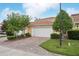 Home exterior showcasing a brick driveway, two-car garage and tropical landscaping at 8430 Leatherleaf Ln, Orlando, FL 32827