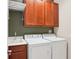 Well-equipped laundry room featuring a utility sink, white washer and dryer, and dark wood cabinets at 8430 Leatherleaf Ln, Orlando, FL 32827
