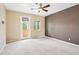 Spacious main bedroom with a ceiling fan, neutral carpet, textured wall, and outdoor balcony access at 8430 Leatherleaf Ln, Orlando, FL 32827