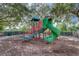 Community playground features a green slide and steps for children to play on with soft ground covering at 8430 Leatherleaf Ln, Orlando, FL 32827