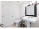 Clean bathroom with a pedestal sink, toilet, framed mirror, and a tiled floor, offering a minimalist and functional space at 9062 Dancy Tree Ct, Orlando, FL 32836