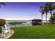 Green backyard featuring chairs, an iron fence, and water views at twilight at 9146 Bay Point Dr, Orlando, FL 32819