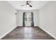 Spacious bedroom with wood-look flooring, a ceiling fan, and a window with decorative curtains at 9900 Sweepstakes Ln # 1, Orlando, FL 32837