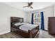 Bedroom featuring a dark wood bed frame, ceiling fan, and a window with blue curtains at 9900 Sweepstakes Ln # 1, Orlando, FL 32837
