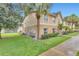 Condo exterior with lush green lawn, mature trees, and tan walls, offering a serene view at 9900 Sweepstakes Ln # 1, Orlando, FL 32837