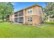 Exterior view of back of a two story tan building with a screened patio, grass and some landscaping at 9900 Sweepstakes Ln # 1, Orlando, FL 32837