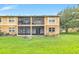 The back of this tan building has a screened patio with grass and landscaping at 9900 Sweepstakes Ln # 1, Orlando, FL 32837