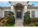 Inviting front entrance with a dark teal door, complemented by lush greenery and sidelight windows at 3956 Shadowind Way, Gotha, FL 34734
