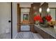 Stylish bathroom vanity showcasing a marble countertop, vessel sink, modern fixtures, decorative mirror and flowers at 11103 Bridge House Rd, Windermere, FL 34786