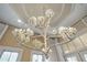 An ornate and modern chandelier hangs from the trey ceiling in a room with large windows and elegant decor at 11103 Bridge House Rd, Windermere, FL 34786