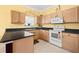 Compact kitchen featuring wood cabinets, black countertops, and essential appliances at 118 Ventana Dr, Kissimmee, FL 34759