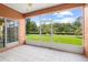 Screened-in patio with tile flooring offering an expansive view of the landscaped backyard and blue skies at 118 Ventana Dr, Kissimmee, FL 34759