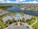 Aerial view of community clubhouse with large pool, parking, and landscaping, near a scenic lake at 13461 Panama Beach Ct, Orlando, FL 32827