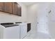 Modern laundry room featuring a front-load washer and dryer, dark cabinets, and sleek tile flooring at 13461 Panama Beach Ct, Orlando, FL 32827