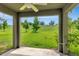 Backyard with a large, well-maintained lawn surrounded by trees, viewed from covered patio at 144 Williamson Dr, Davenport, FL 33897