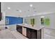 Open kitchen features a large island with granite countertops, dark cabinets, and modern lighting at 144 Williamson Dr, Davenport, FL 33897