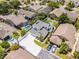 An aerial view of a two-story house with white driveway, green backyard, solar panels on a grey roof, and manicured palm trees at 14423 Tambourine Dr, Orlando, FL 32837