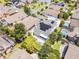 Aerial view featuring a well-landscaped property with a white driveway, green backyard, and modern solar panels on grey shingled roof at 14423 Tambourine Dr, Orlando, FL 32837